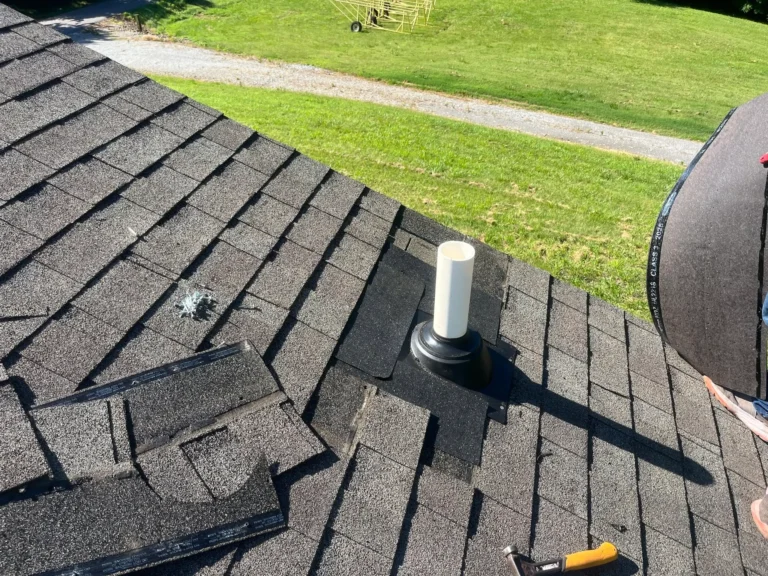 Damaged shingles lifted around a roof vent pipe
