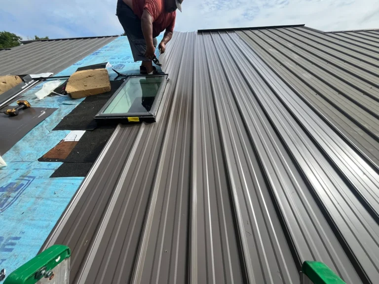 Roofer installing metal roof panels next to a skylight