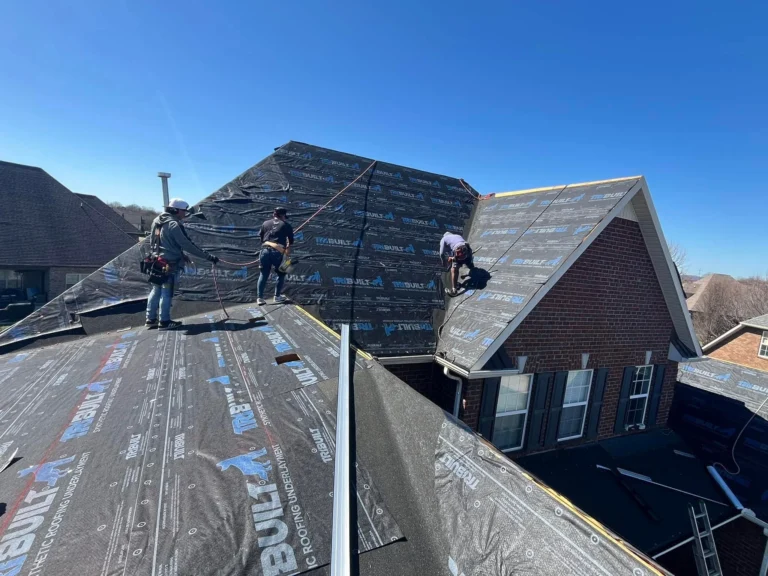 Roofers installing underlayment on a brick home
